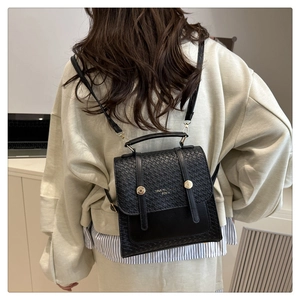 Détail d'un sac à dos noir en cuir tressé avec boucles dorées porté par un mannequin