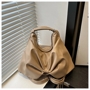 Detail of beige hobo bag with unique bow-shaped pleated design and matte leather texture
