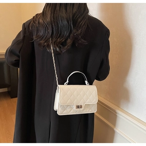Detailed close-up of a white quilted crossbody bag with chain strap and metal turn-lock