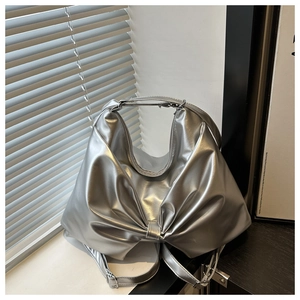 Detail of silver metallic handbag featuring a large bow design and adjustable strap