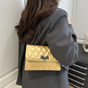 Sac bandoulière matelassé doré avec fermoir papillon et bandoulière chaîne