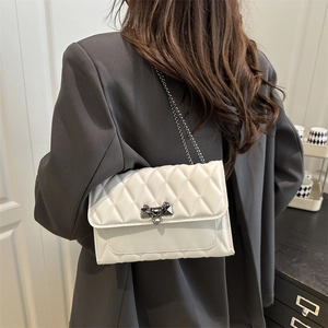 Sac bandoulière blanc matelassé avec chaîne argentée et fermoir sur un modèle