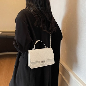 White quilted crossbody bag with silver chain strap shown on a black suit model