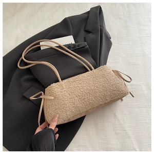 Detailed close-up of beige faux shearling baguette bag featuring stylish side leather drawstring