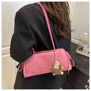 Close-up of pink faux shearling phone bag with cute brown plush monster charm on model