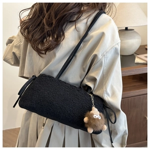 Detail of black faux shearling crossbody bag with cute monster plush charm on shoulder