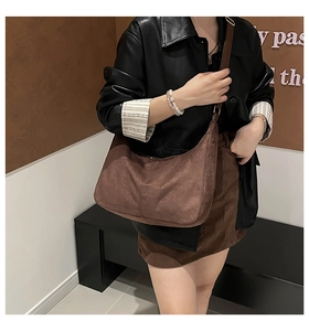 Primer plano del bolso hobo de gamuza marrón mate con correa ajustable en modelo