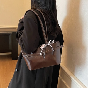 Sac fourre-tout en cuir marron avec ruban décoratif et boucle porté à l'épaule