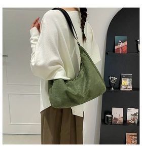 Detalle del bolso hobo de ante verde bosque con correa ancha negra en modelo