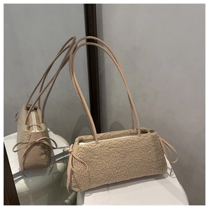 Detail view of beige faux shearling texture with leather bow and zipper on mini phone bag
