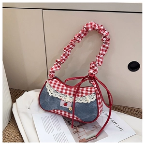 Detailed shot of red plaid and denim patchwork bag with lace trim and cherry embroidery