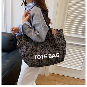 Detail of the leopard print tote bag featuring a leather patch and white text branding