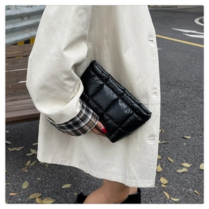Close-up of black quilted nylon clutch bag with geometric stitching and glossy finish
