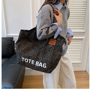 Close-up of leopard print tote bag in canvas featuring bold TOTE BAG lettering and detail