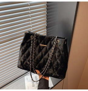 Close-up of black quilted tote bag with gold logo and elegant chain strap details