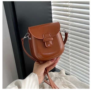 Detail view of JARYUN brown saddle bag showing polished PU leather and flap design