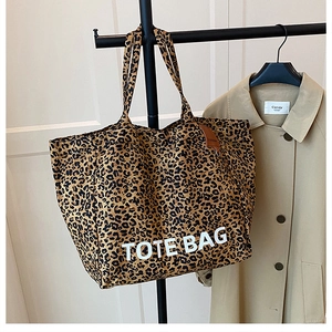 Detail of leopard print canvas tote bag featuring large white TOTE BAG lettering on front