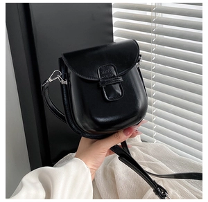 Detailed close-up of glossy black leather crossbody phone bag with embossed logo detail