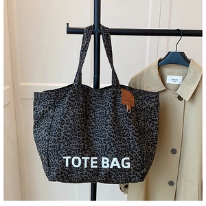 Detail of leopard print tote bag with white TOTE BAG lettering and brown leather tag