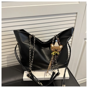 Détail du sac cabas en similicuir noir avec bandoulière chaîne dorée et ours en peluche