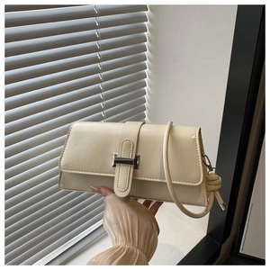 Close-up of cream rectangular shoulder bag with silver lock and knotted strap detail
