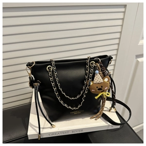 Détail d'un sac seau en cuir noir avec bandoulière chaîne et charmant ours en peluche