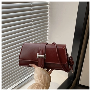 Detail view of burgundy leather shoulder bag with silver buckle and knot decoration