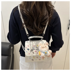 Détail d'un mini sac à dos en cuir blanc avec motifs pop art et breloque ours mignon