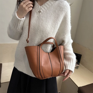 Brown faux leather tote bag with vertical stitching and adjustable shoulder strap