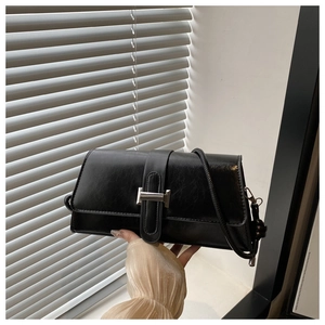 Close-up of black textured faux leather handbag featuring a silver H-shaped metal buckle