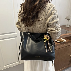 Sac seau noir en cuir avec bandoulière chaîne et breloque ours porté par un mannequin