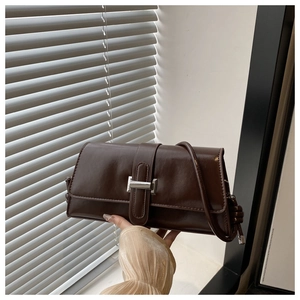 Detailed macro view of the glossy chocolate brown leather and silver buckle of this stylish bag