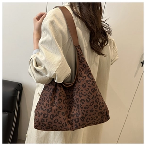 Detailed view of large leopard print tote bag featuring brown leather shoulder strap
