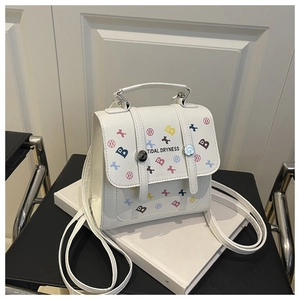 Vue détaillée du mini sac à dos blanc avec imprimés d'os colorés et fermoir métallique sur livres