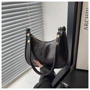 Detail of dark brown croissant bag featuring vintage finish and gold rivet accents