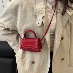 Red patent leather mini top handle bag with curved base and slender shoulder strap