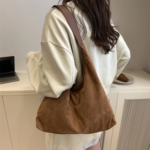 Brown suede tote bag with leather straps worn by model in a minimalist office setting