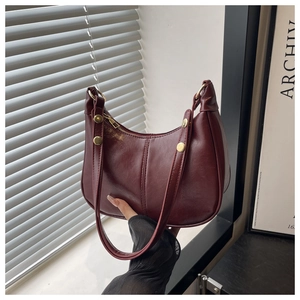 Detailed close-up of glossy wine red leather hobo bag with vintage texture and gold studs