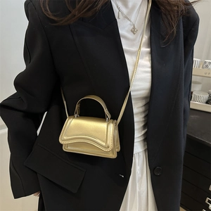 Chic gold hourglass handbag in metallic finish with top handle and slim crossbody strap