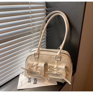 Detail of cream PU leather shoulder bag with decorative bows and ruffled pockets
