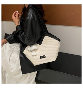 Detail of corduroy tote bag with black trim and fluffy cloud keychain accessory