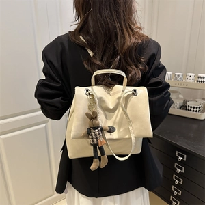 Minimalistischer cremeweißer Lederrucksack mit Hasenanhänger am Modell getragen