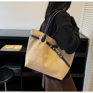 Detail of camel tote bag with side belt buckle design and slim black shoulder straps
