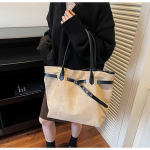 Detail of light camel tote bag with black leather straps and metal eyelet accents