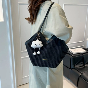 Black corduroy tote bag with V-shaped opening and cute plush charm shown on model