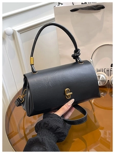 Detail of black crossbody bag featuring vintage leather texture and gold twist lock