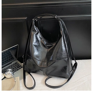 Close-up of black glossy textured faux leather tote showing the adjustable shoulder strap