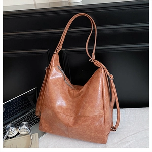 Macro shot of brown retro PU leather texture and cross stitching detail on large tote bag