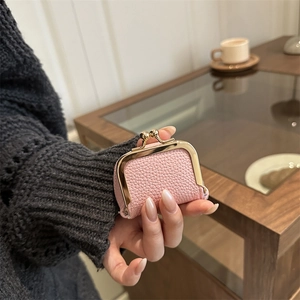 Mini porte-monnaie rose en cuir grainé avec fermoir clic-clac doré dans la main