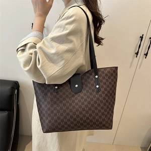 Brown monogram tote bag with M patterns shown from a side view by a model